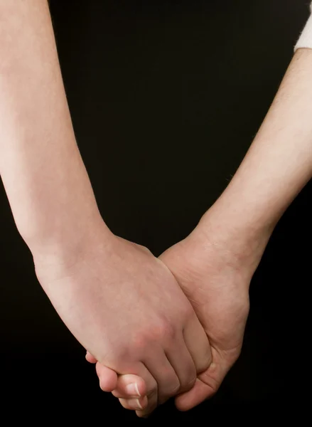Two hands holding each other on black background — Stock Photo, Image