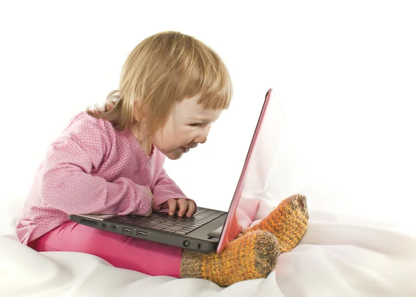 Baby girl looking onto the laptop's screen on white background — Stock Photo, Image