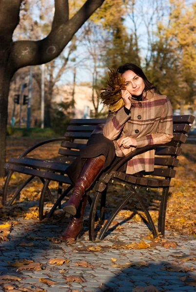 Beautiful young woman on a bench in autumn — Stock Photo, Image