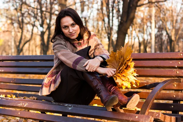 Krásná mladá žena na lavičce na podzim — Stock fotografie