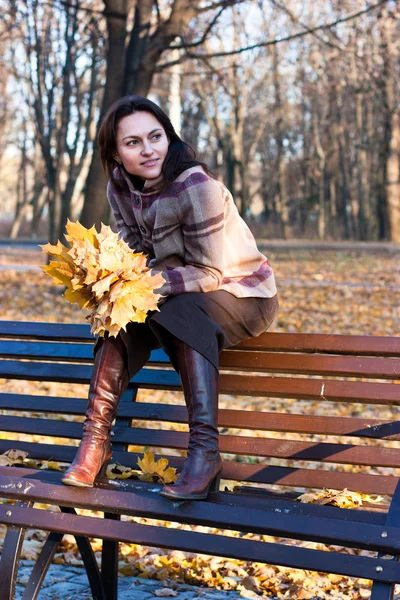 Красивая молодая женщина на скамейке осенью — стоковое фото