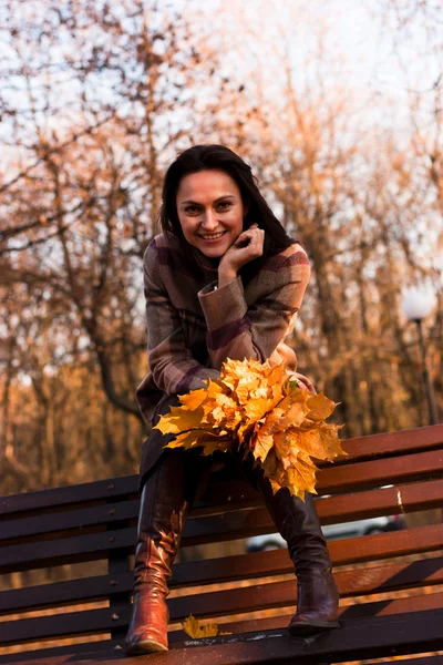 Krásná mladá žena na lavičce na podzim — Stock fotografie