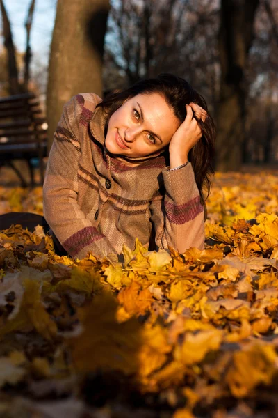 Hermosa mujer joven acostada en hojas de otoño — Foto de Stock