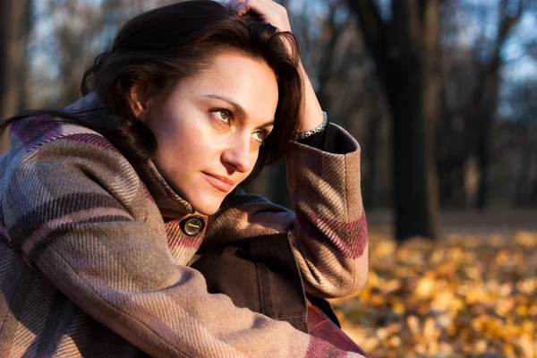 Krásná mladá žena sedící na podzim listy — Stock fotografie