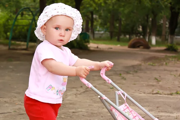 Kis baba lány egy babakocsi, játszótér — Stock Fotó