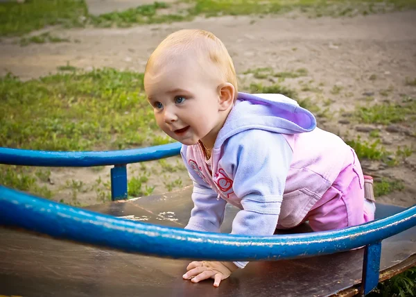 Beautiful baby girl climbing a slide in playground — Stock Photo, Image