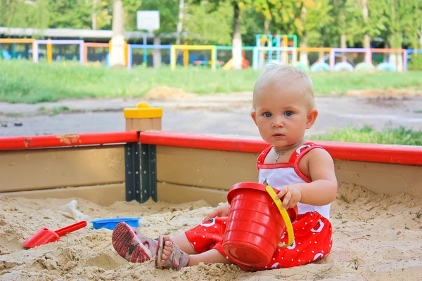 Niña sentada jugando en una caja de arena en el patio al aire libre —  Fotos de Stock