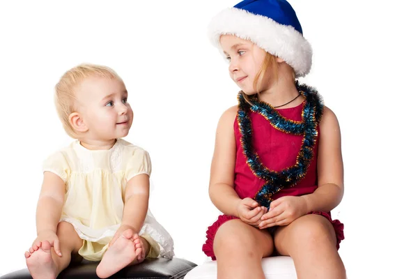 サンタさんの帽子の sibiling 姉妹を見ている赤ちゃん — ストック写真