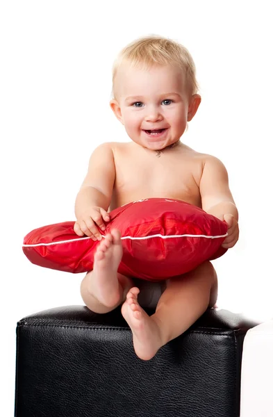 เด็กที่สวยงามนั่งกับหมอนสีแดงรูปหัวใจ — ภาพถ่ายสต็อก