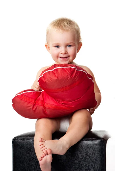 เด็กที่สวยงามนั่งกับหมอนสีแดงรูปหัวใจ — ภาพถ่ายสต็อก