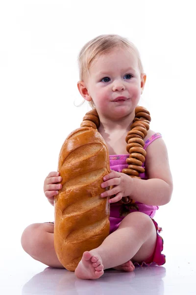 Baby hält einen Laib Brot in Rollperlen — Stockfoto