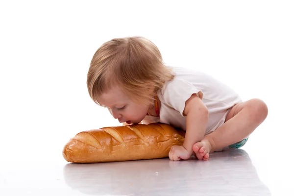 Baby trying to bite a loaf of bread — Stock Photo, Image