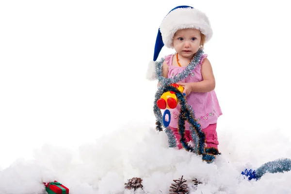 Baby in Santa's hat in tinsel and artificial snow — Stock Photo, Image
