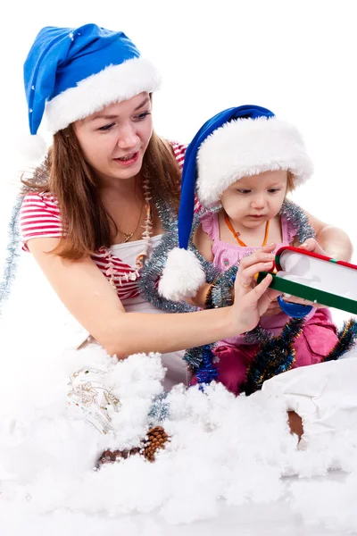 Madre e hija en el sombrero de Santa sentado en nieve artificial — Foto de Stock