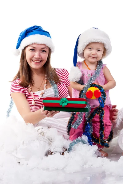 人工雪で座っているサンタさんの帽子で母と娘 — ストック写真