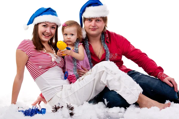 人工雪の中で横になっているサンタさんの帽子の家族 — ストック写真