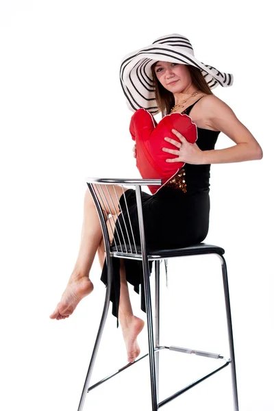 Красивая молодая девушка сидит на барном стуле с красной подушкой сердца — стоковое фото