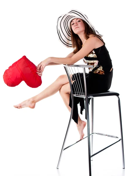 Beautiful young girl sitting on a bar chair with red heart pillow — Stock Photo, Image