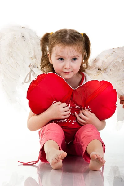 Vacker flicka sitter med hjärtat formade röd kudde — Stockfoto
