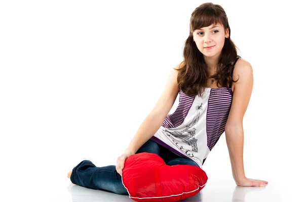 Beautiful girl sitting with heart shaped red pillow — Stock Photo, Image