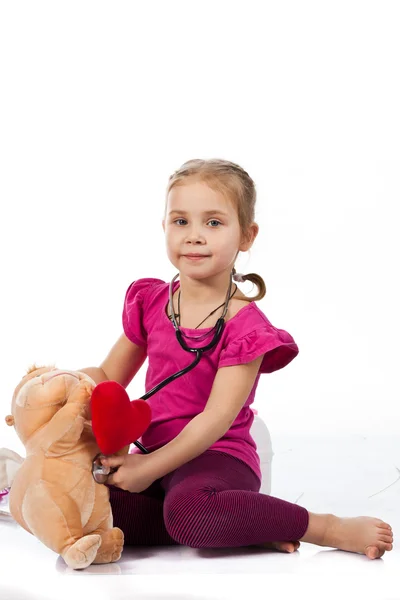Hermosa chica jugando al doctor con una muñeca — Foto de Stock