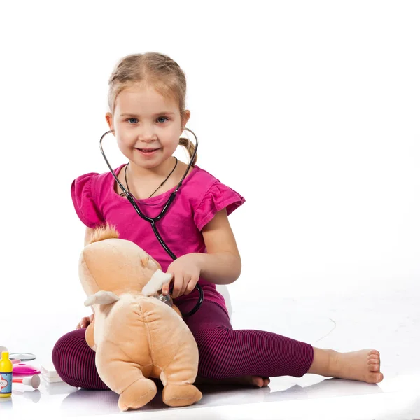 Hermosa chica jugando al doctor con una muñeca — Foto de Stock