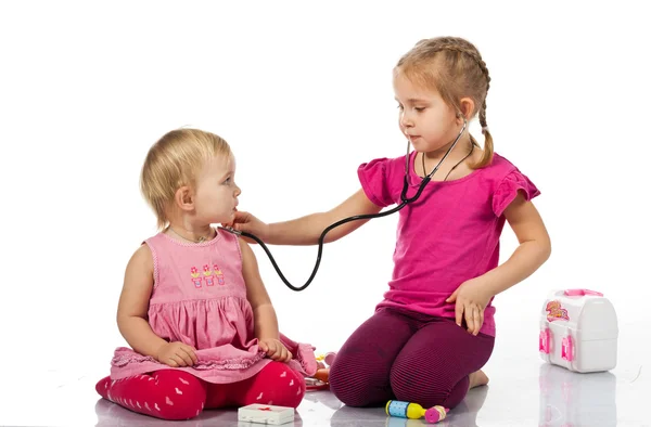Дети играют в доктора с куклой — стоковое фото