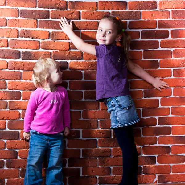 Barnen poserar nära tegelvägg — Stockfoto