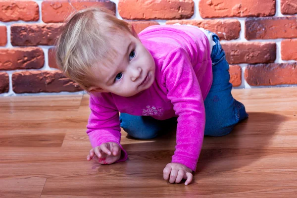 Menina bonita rastejando no chão perto da parede de ruptura — Fotografia de Stock