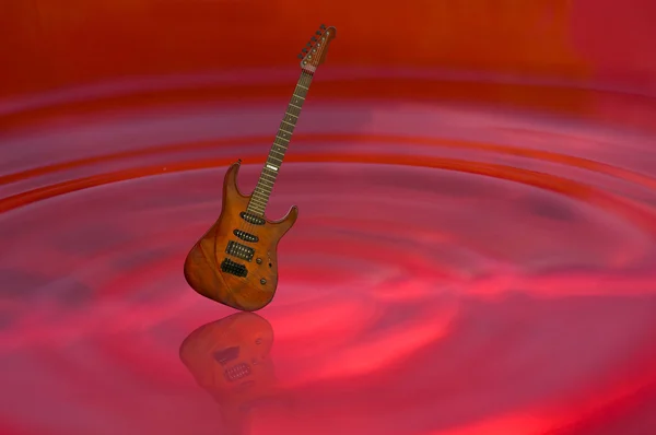 Guitar on red water — Zdjęcie stockowe