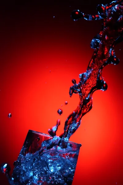 Spritzwasser Aus Der Tasse Auf Rotem Hintergrund — Stockfoto