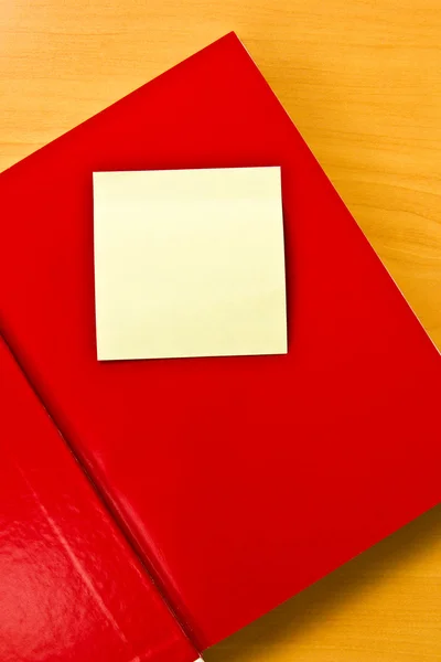 Желтая записка на красной тетради — стоковое фото