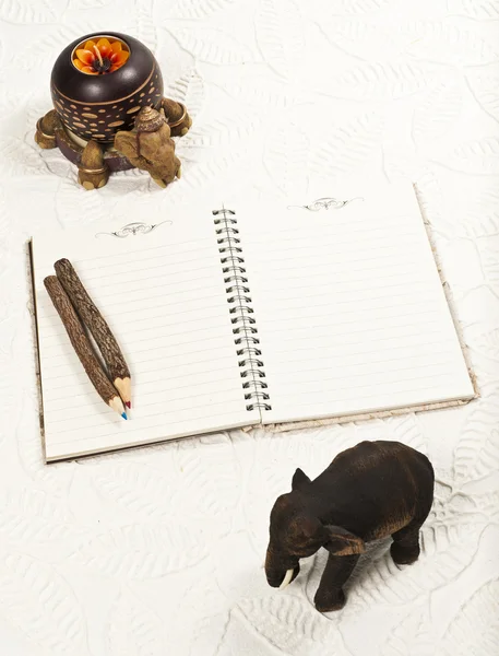 Notebook a barevné tužky ozdobíme dřevěný slon — Stock fotografie