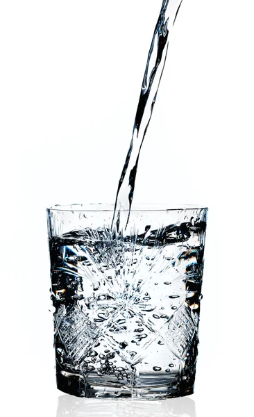Água derramando em um vidro, fundo branco — Fotografia de Stock