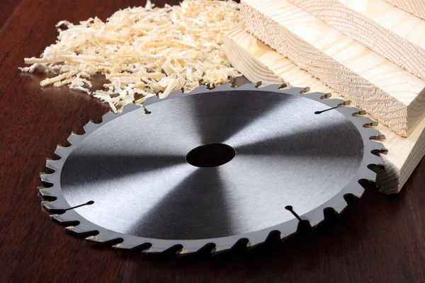 Circ saw blades, planks and shavings on dark background — Stock Photo, Image