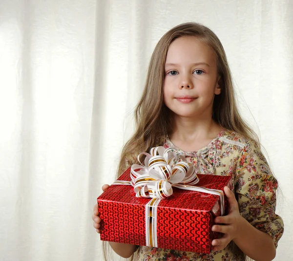 Menina segura uma caixa vermelha com um presente — Fotografia de Stock