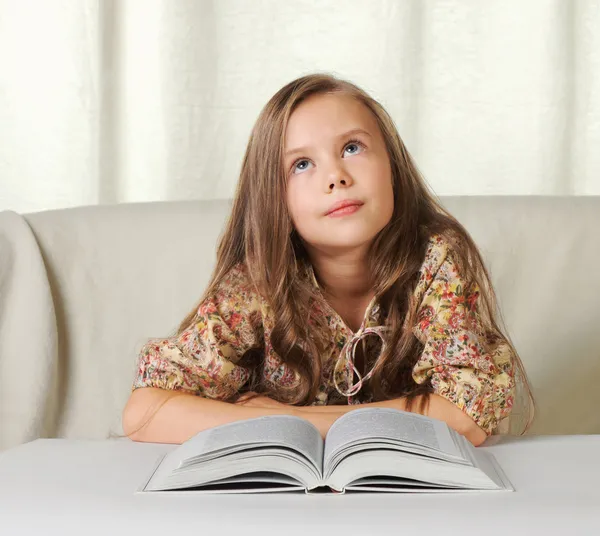 Kleines Mädchen träumt beim Lesen des Buches — Stockfoto