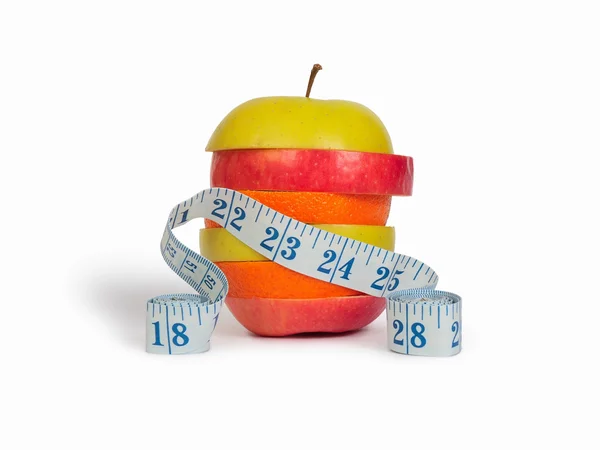 Slices of apples and orange as one fruit and a measuring tape — Stock Photo, Image