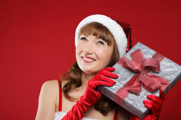 Menina encantadora jovem vestida como Papai Noel detém um presente na forma de coração em h — Fotografia de Stock