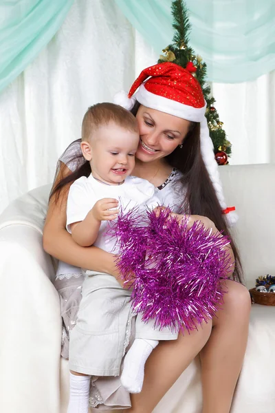 Mamá y su hijo cerca de un árbol de pieles de Navidad abre el regalo —  Fotos de Stock