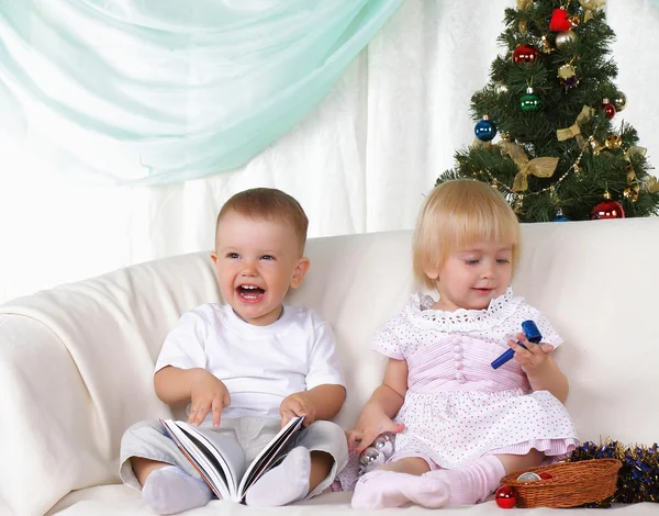 Дети играют рядом с рождественской елкой — стоковое фото