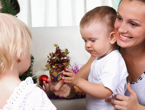 Mamá y los niños se sientan cerca de un árbol de pieles de Navidad —  Fotos de Stock