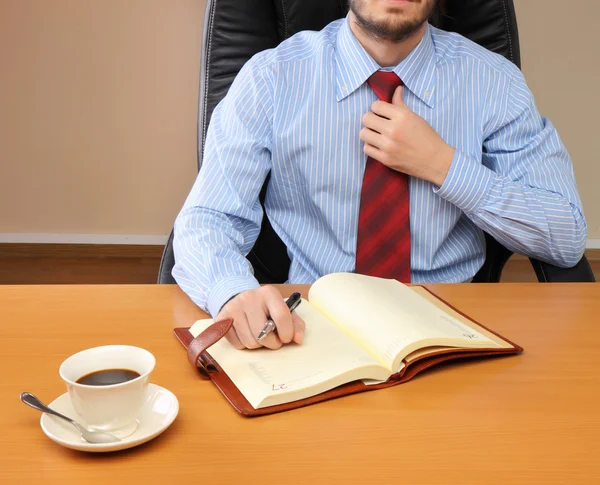 Affärsman korrigerar en slips på sin arbetsplats. — Stockfoto