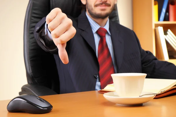 Biznesmen w swoim miejscu pracy pokazuje kciuk w dół. — Zdjęcie stockowe