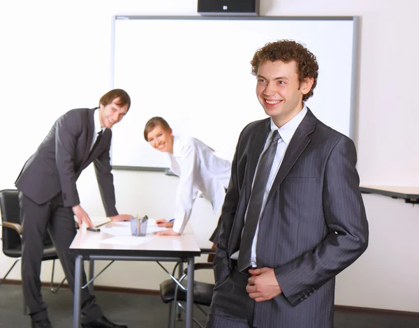 Retrato del hombre de negocios con compañeros de equipo discutiendo en segundo plano —  Fotos de Stock