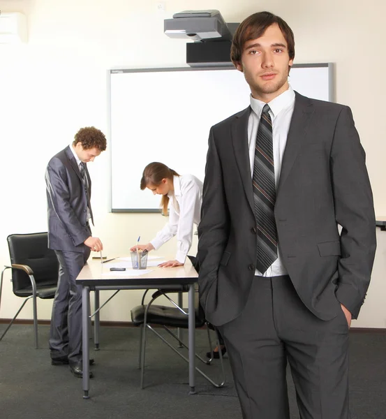 Porträt eines Geschäftsmannes mit Teamkollegen, die im Hintergrund diskutieren Stockbild