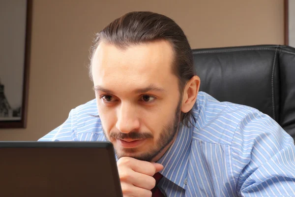 Uomo d'affari al suo sguardo sul posto di lavoro nel computer portatile . — Foto Stock