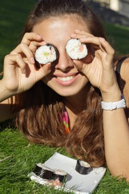 Beautiful girl hold rolls or sushi near eyes funny clipart