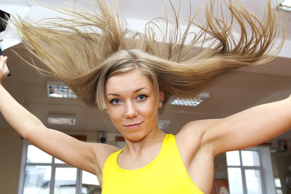 Блондинка с летающими волосами прыгает в спортзале — стоковое фото