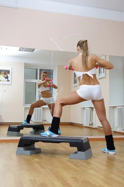 Chica en paso mantenga mancuernas en gimnasio de fitness —  Fotos de Stock